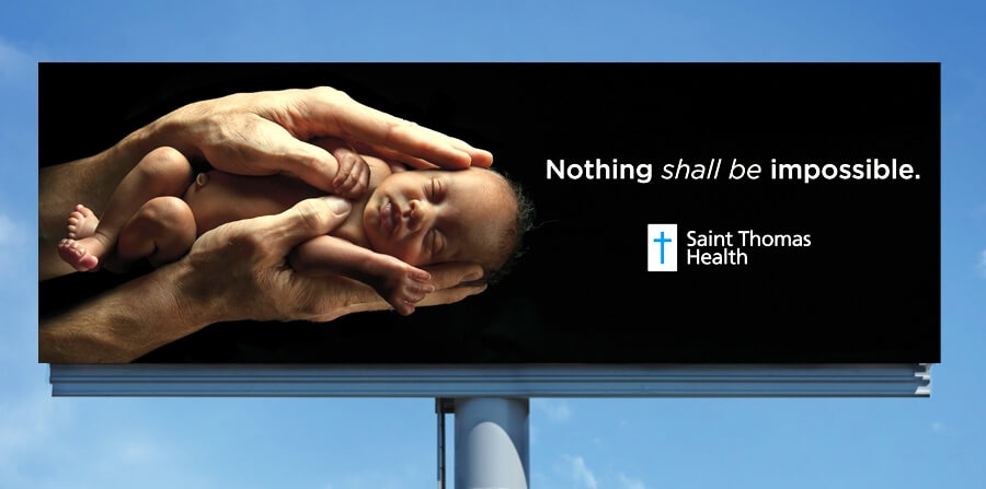 Billboard shows a newborn baby in the hands of a doctor and the words Nothing shall be impossible from Saint Thomas Health